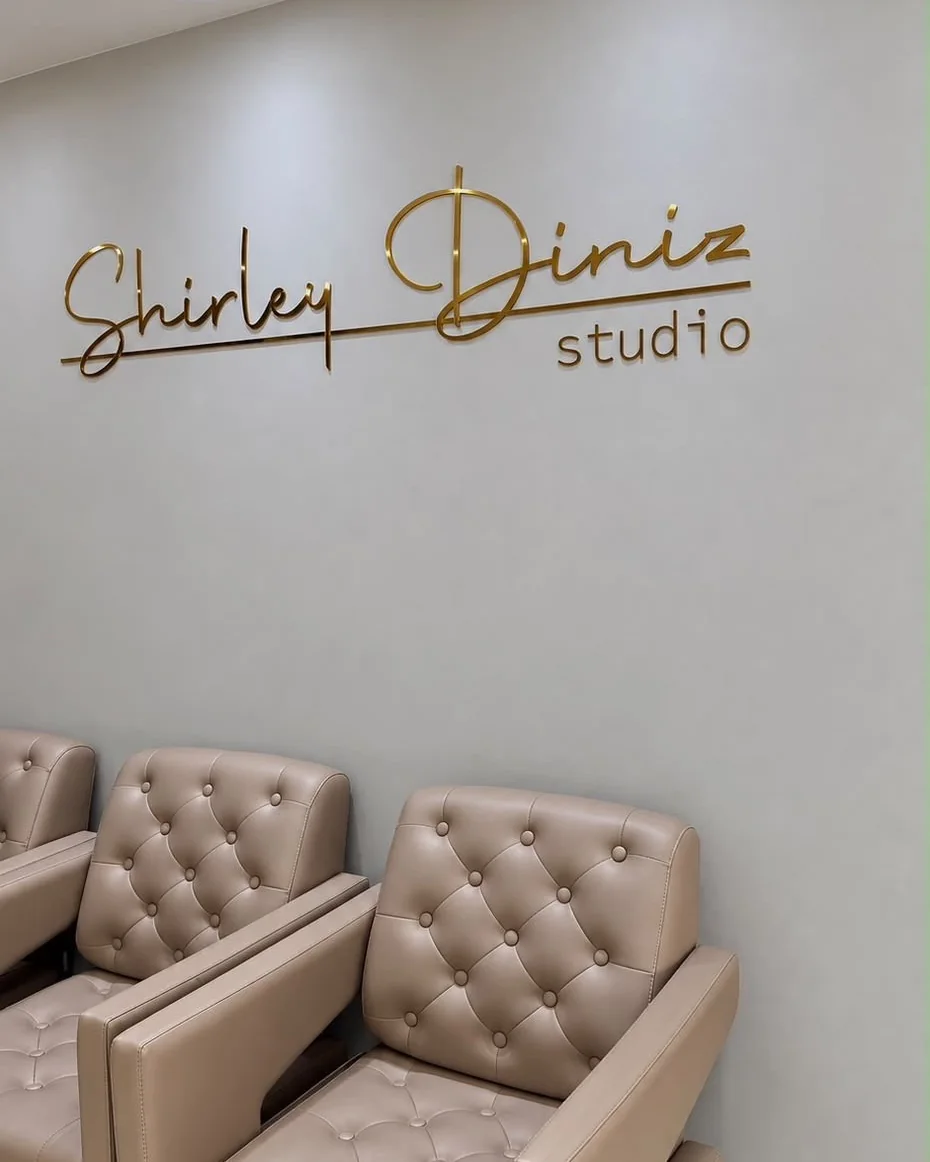 Logo dourada do Shirley Diniz Studio e poltronas de espera